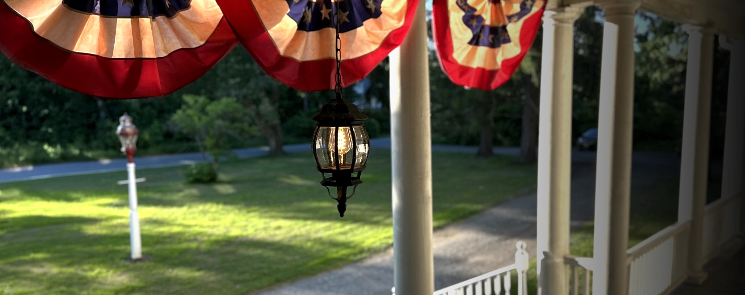 Front porch of Idylease in Newfoundland, New Jersey, with patriotic bunting in evening light