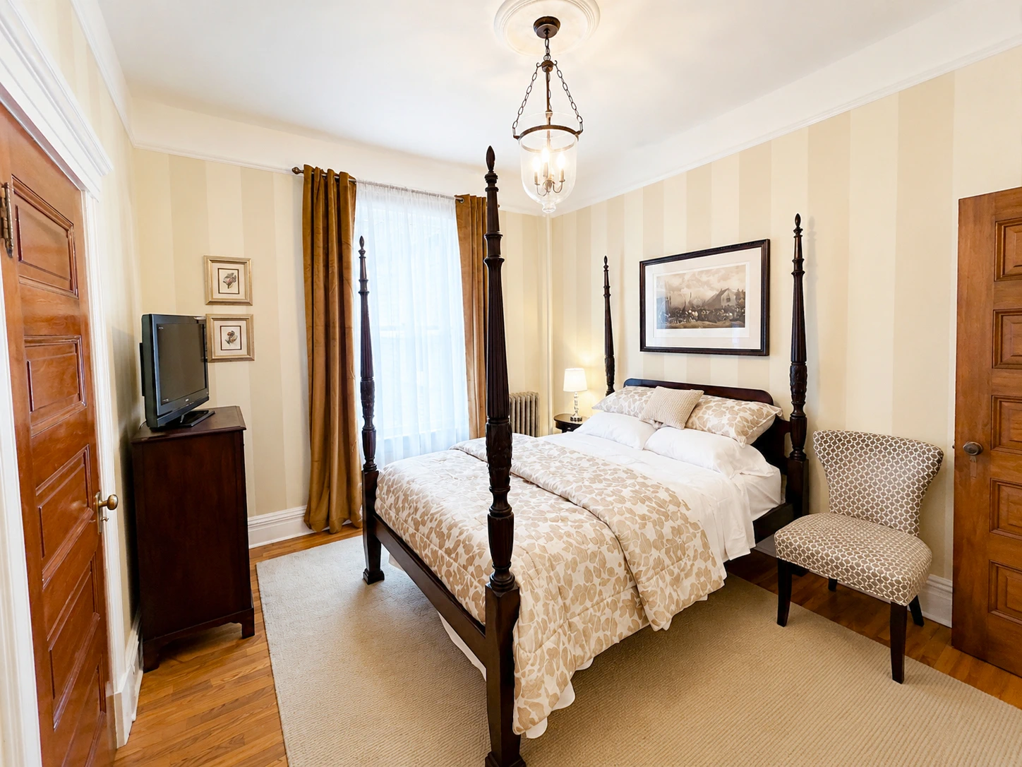 Guest room at Idylease with a four-poster bed, original wood doors, striped walls, tall window, and seating area